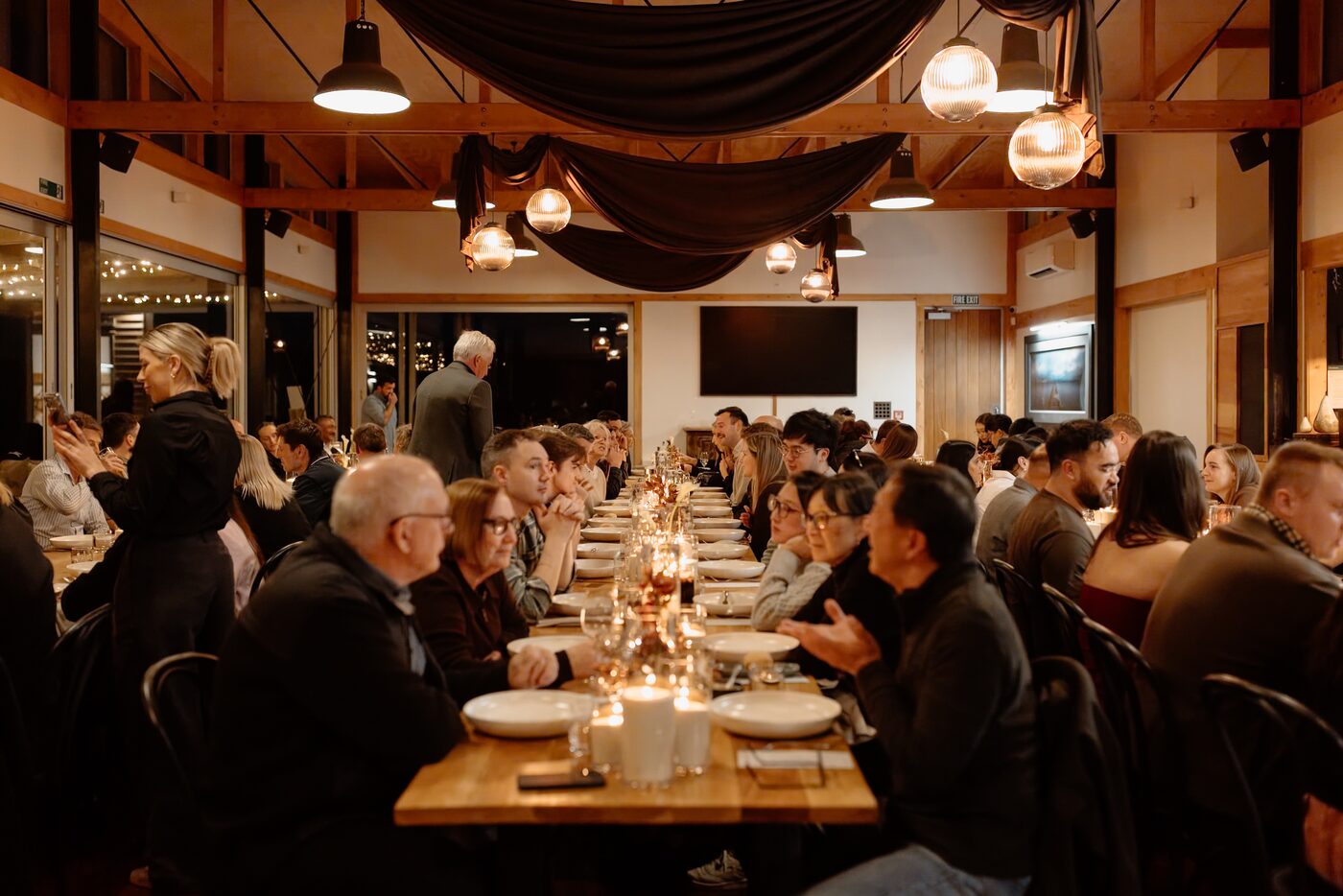 Guests seated along a candlelit long table inside The Lodge